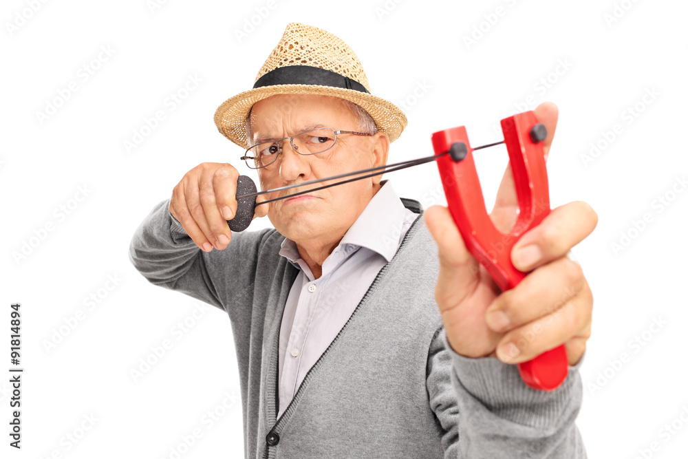 Angry senior aiming to shoot a rock with a slingshot Angry senior aiming to shoot a rock with a slingshot