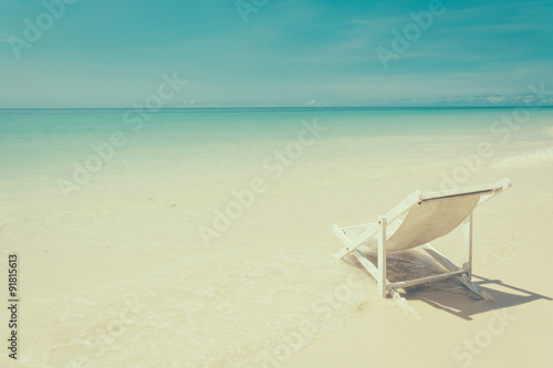 beach chair on beach with blue sky - soft focus with film filter