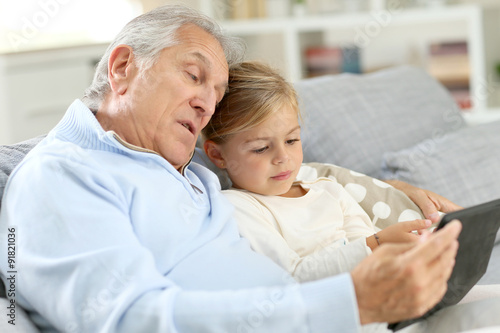 Little girl with grandpa playing with digital tablet