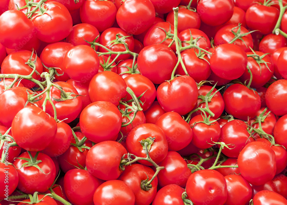 A lot of ripe red cherry tomatoes on the market close up on sunn