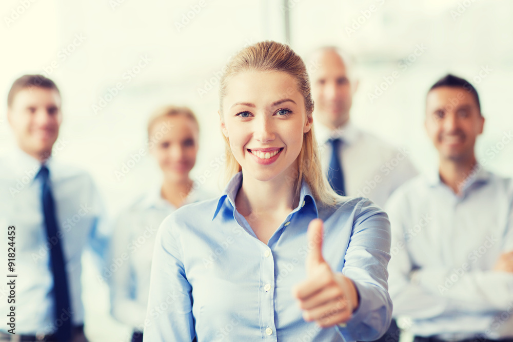smiling businesswoman showing thumbs up in office smiling businesswoman showing thumbs up in office