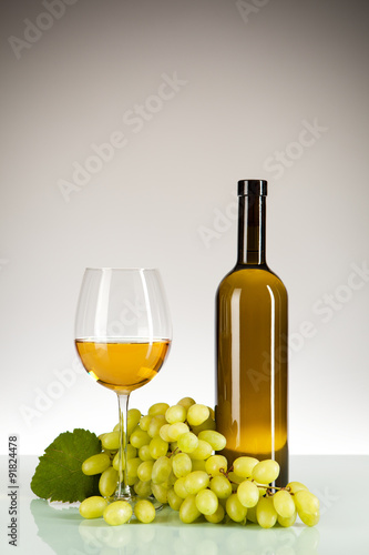 Weißwein im Glas und in der Flasche mit Weintrauben