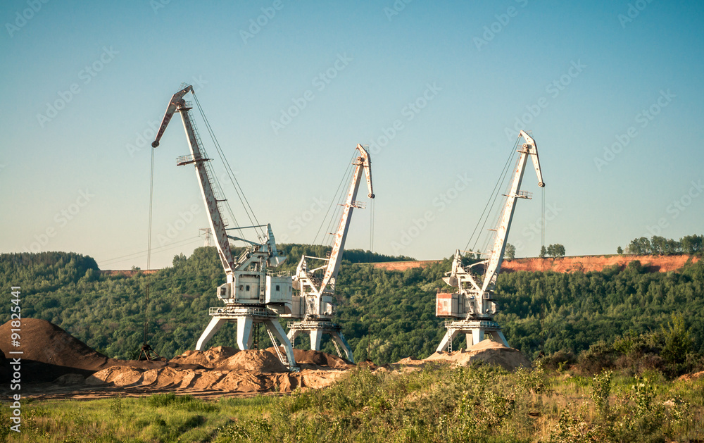 Cranes mining sand against the blue sky