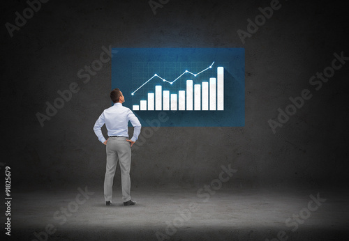 businessman looking at chart over concrete room