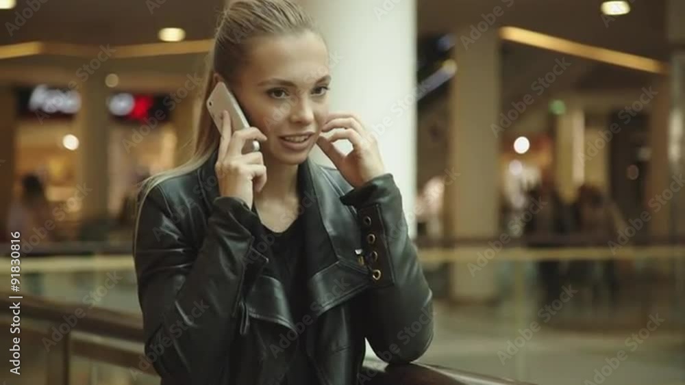 Beautiful girl with long hair, talking on the phone in the mall Beautiful girl with long hair, talking on the phone in the mall