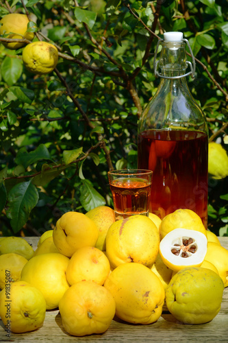 Tincture of quince and fruit on a wooden table.