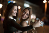 Girlfriends taking self picture with smartphoneat night city