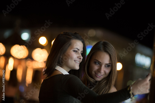 Girlfriends taking self picture with smartphoneat night city © antgor