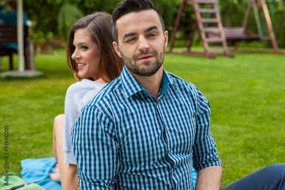 Couple sitting on the blanket in the garden, using tablet and sm Couple sitting on the blanket in the garden, using tablet and sm