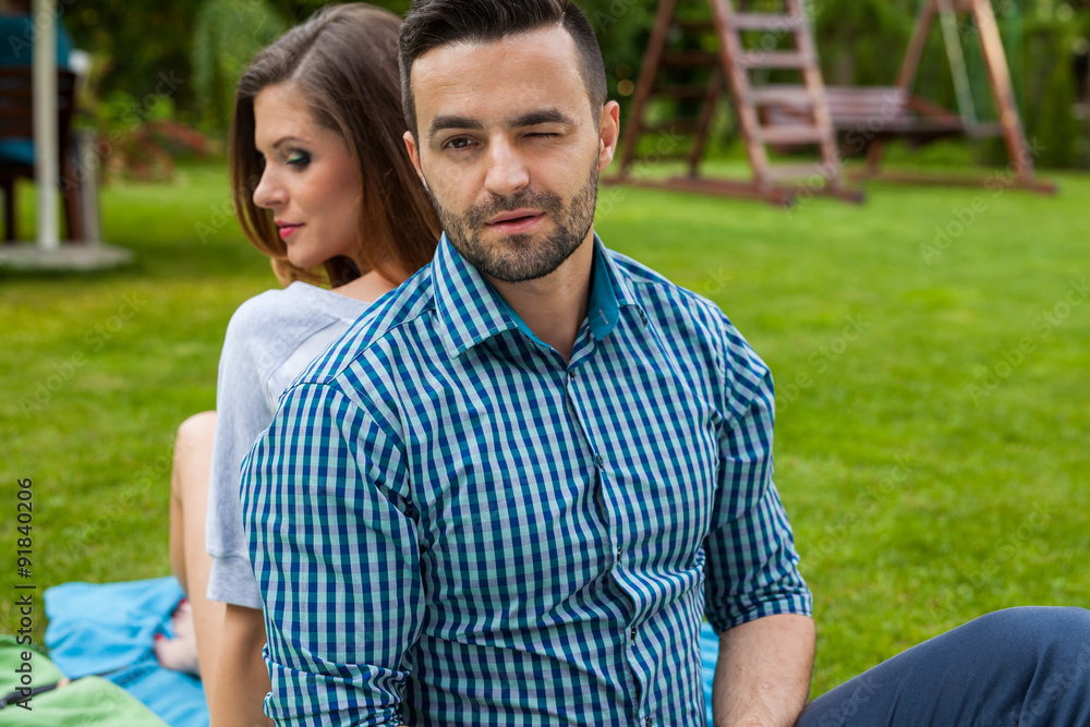 Couple sitting on the blanket in the garden, using tablet and sm