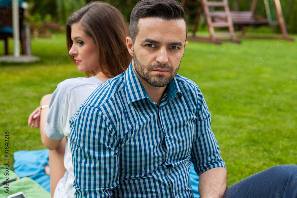 Obraz premium Couple sitting on the blanket in the garden, using tablet and sm