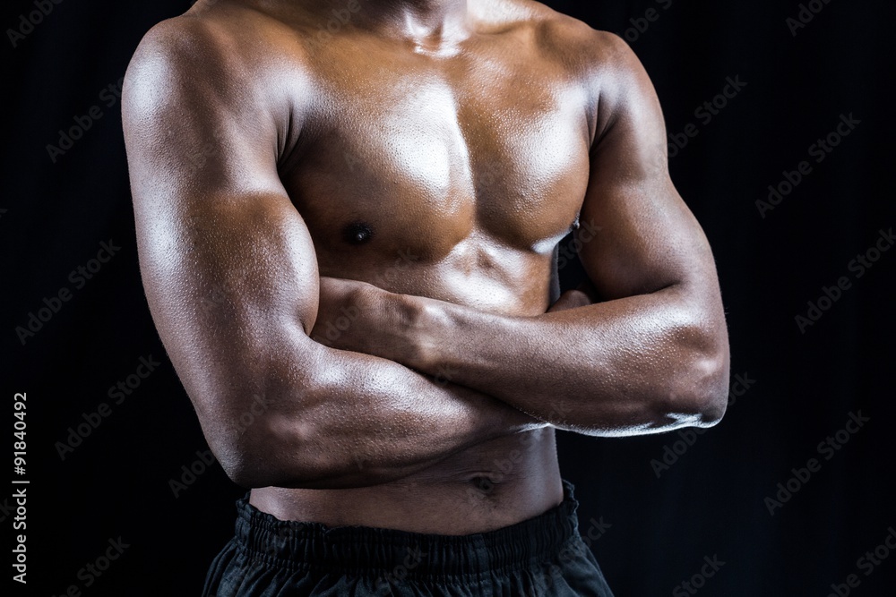 Mid section of shirtless athlete standing with arms crossed Mid section of shirtless athlete standing with arms crossed