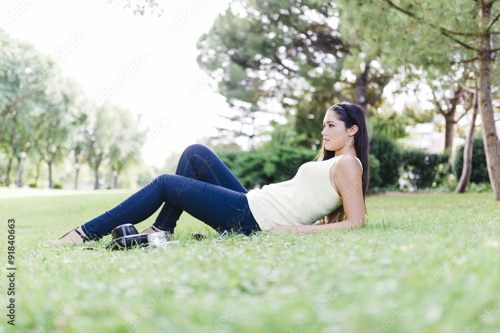 Beautiful young woman lying on the grass in a park with Beautiful young woman lying on the grass in a park with