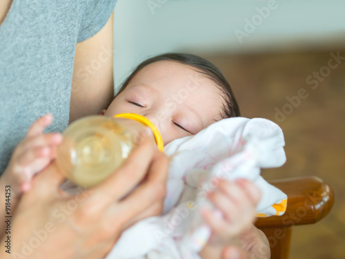 Wallpaper Mural Asian mother feeding bottle her baby while baby sleeping. Torontodigital.ca
