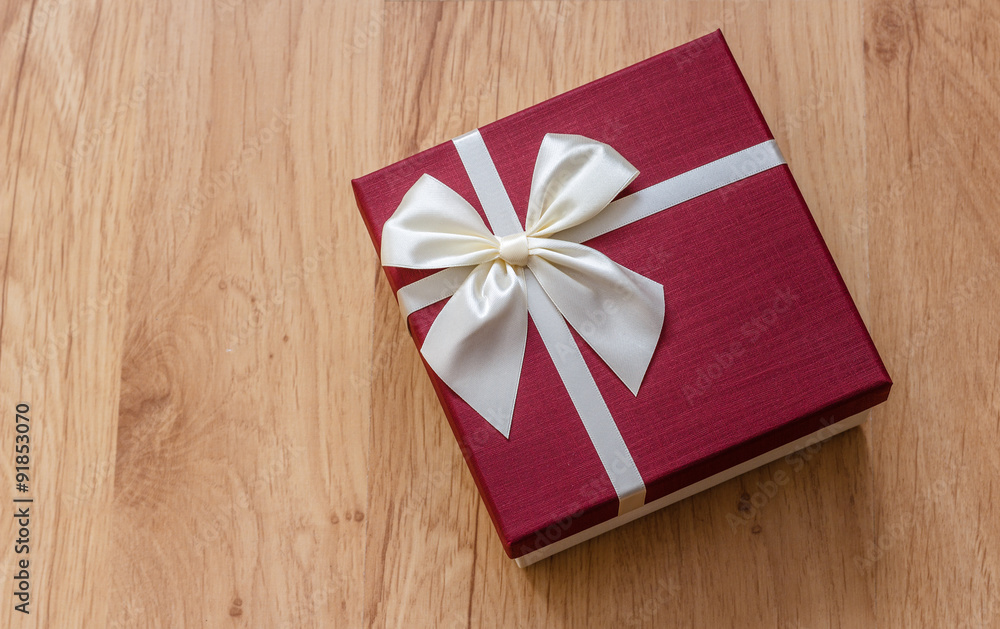 Gift box on wood, burgundy colored white ribbon bow Gift box on wood, burgundy colored white ribbon bow