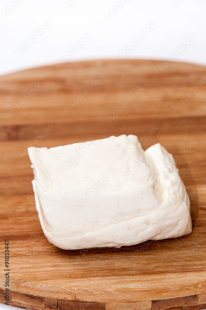 Homemade white cheese on the kitchen wooden board Homemade white cheese on the kitchen wooden board