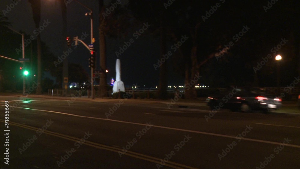 A car travels along a street at night in Santa Monica, California as seen through the rear window at an angle. A car travels along a street at night in Santa Monica, California as seen through the rear window at an angle.
