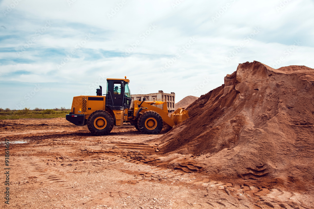 Excavator Loads Gravel into a Truck on a Crushed Stone Quarry Excavator Loads Gravel into a Truck on a Crushed Stone Quarry
