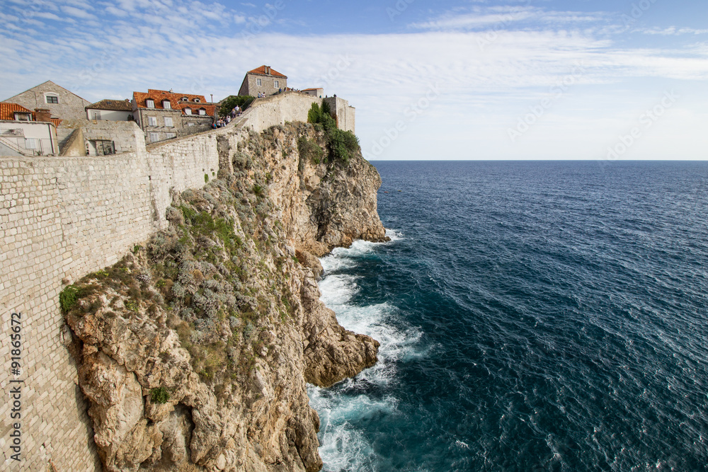 Scenic view of the city walls, steep cliff and ocean in Dubrovnik, Croatia.