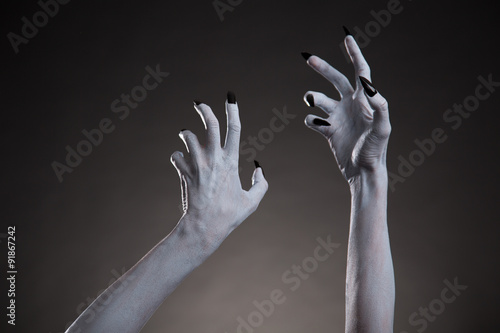 Spooky Halloween white hands with black nails stretching up