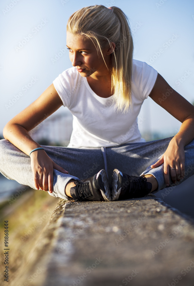 Blonde young girl taking a rest after training, outdoor