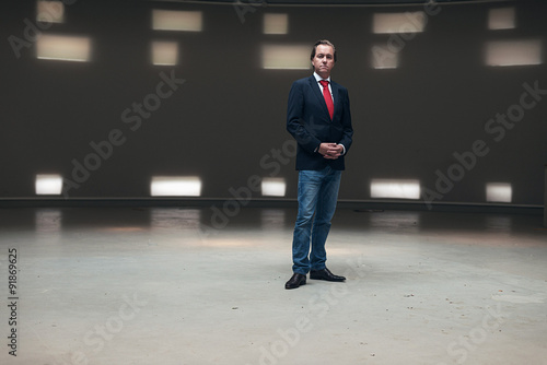 Portrait of young entrepreneur with red tie standing in empty ha