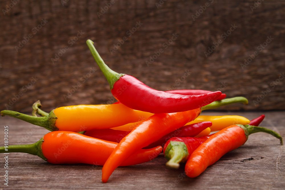 hot red, yellow, orange peppers on the old wooden background