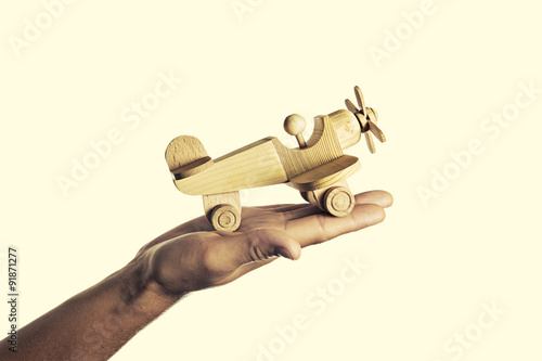 isolated image of a hand with an open palm on which the handmade wooden aircraft