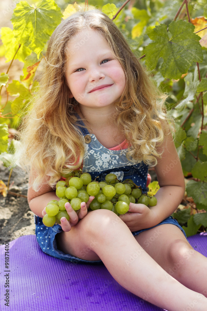 Blonde child girl with grapes in autumn vineyard Blonde child girl with grapes in autumn vineyard