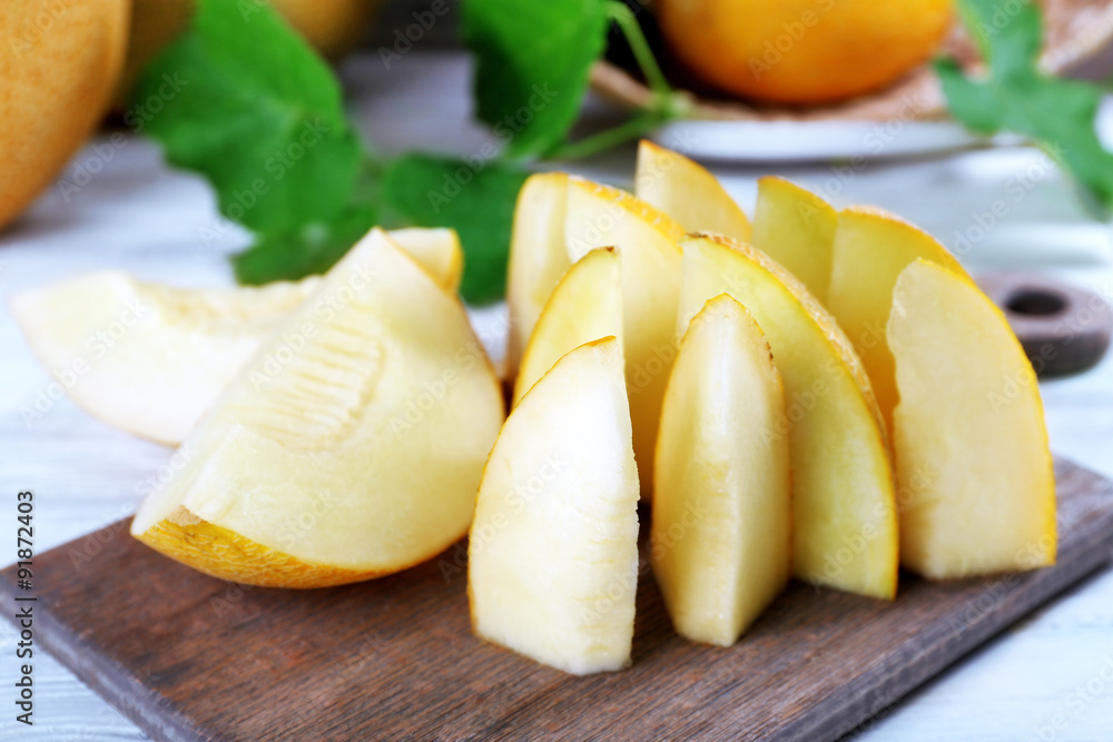 Slices of ripe melons with green leaves on table close up Slices of ripe melons with green leaves on table close up