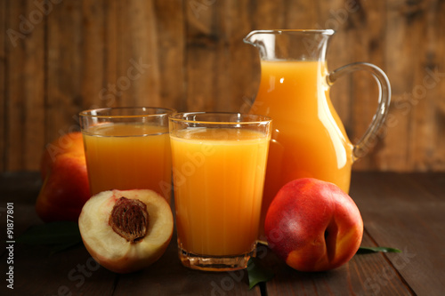 Peach juice and ripe peaches on wooden background