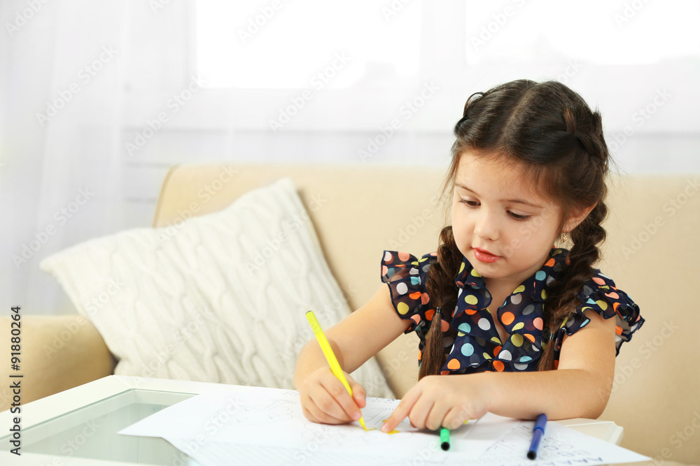 Cute little girl doing her homework, close-up, on home interior background Cute little girl doing her homework, close-up, on home interior background