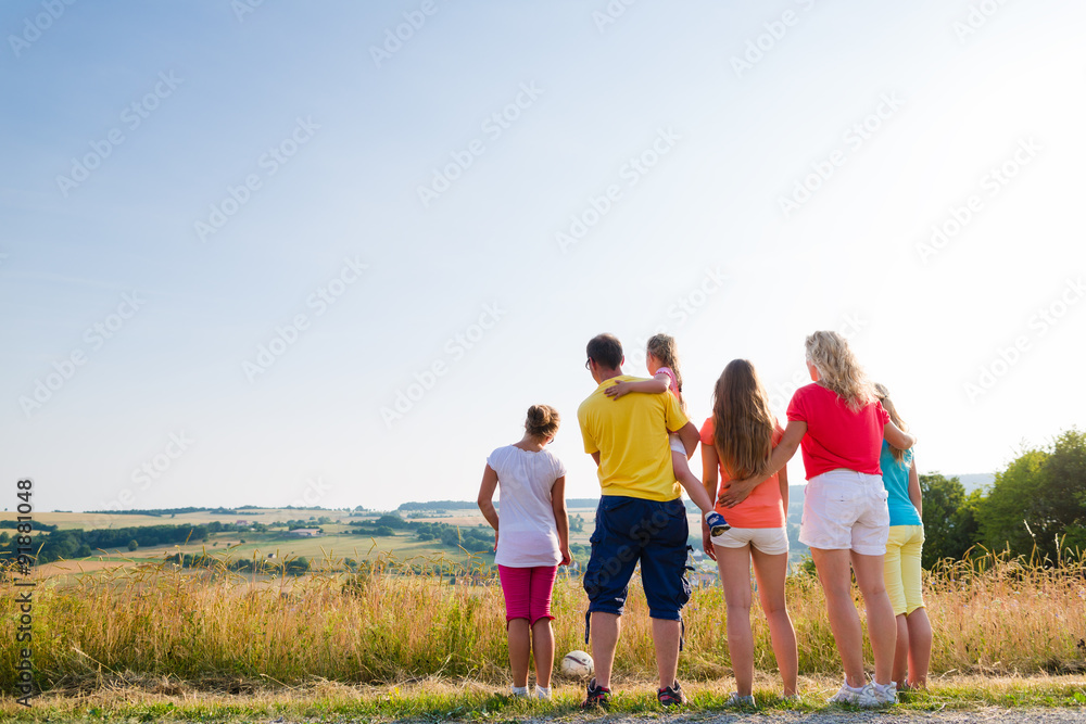 Familie bei Spaziergang betrachtet die Landschaft der Heimat an einem Sommerabend Familie bei Spaziergang betrachtet die Landschaft der Heimat an einem Sommerabend