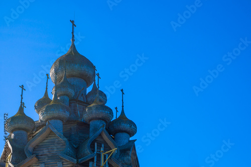 Church of the Intercession  with domes covered with aspen shingles  against bright blue sky photo