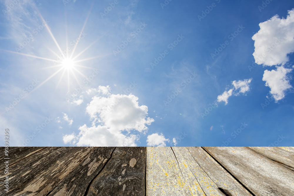 wood floor with sun star and blue sky background.