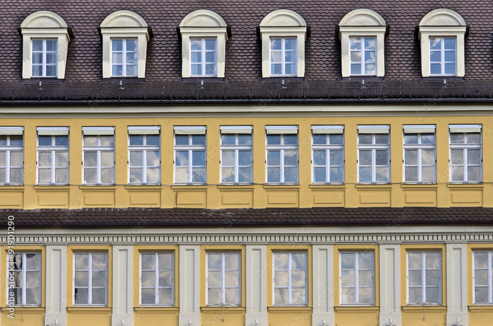 Fototapeta premium Facade with rows of windows.Mansard roof and yellow facade in typical german architecture style building. Munich,Bavaria,Germany.