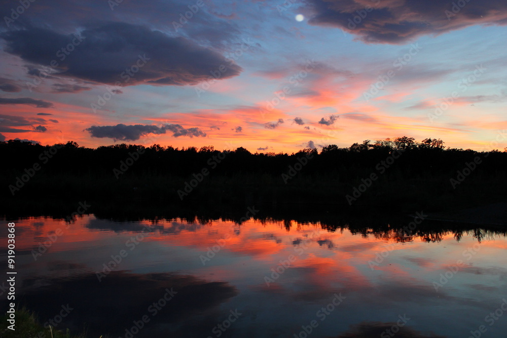 Oranger Himmel beim Sonnenuntergang spiegelt sich im Wasser
