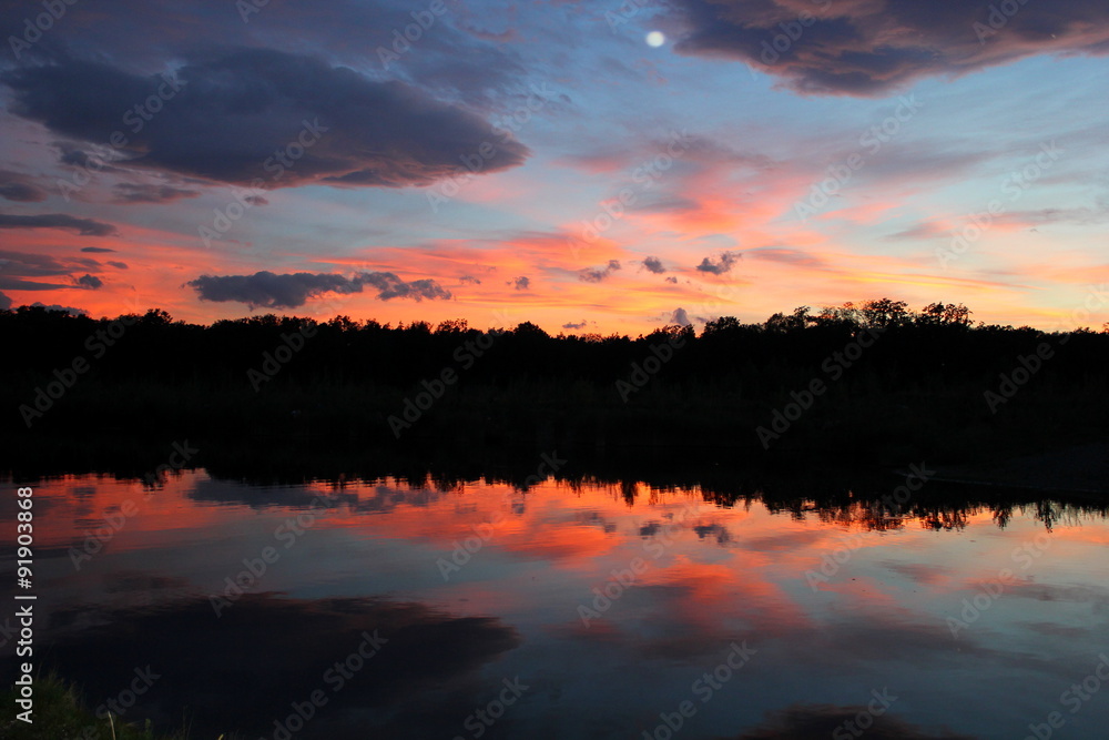 Oranger Himmel beim Sonnenuntergang spiegelt sich im Wasser Oranger Himmel beim Sonnenuntergang spiegelt sich im Wasser