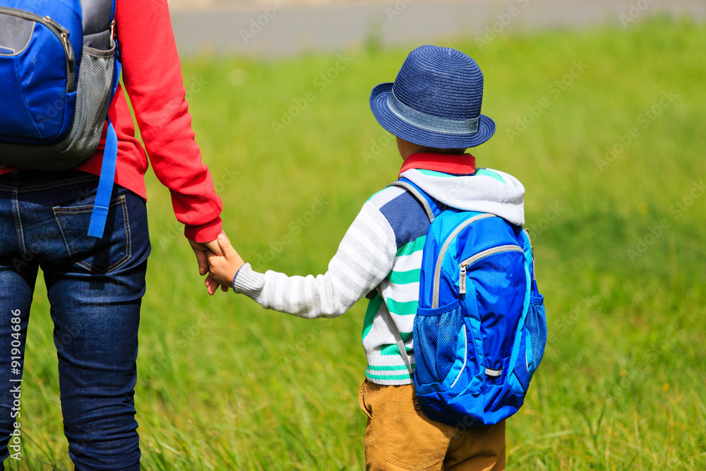 Mother holding hand of little son with backpack outdoors Mother holding hand of little son with backpack outdoors