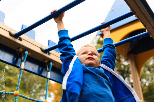 Bild auf Leinwand little boy playing on monkey bars in autumn