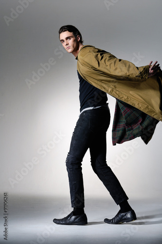 Full body portrait of a young fashion male walking on light background