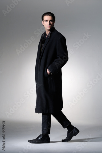 Full body Fashion Shot of a young business man in coat on light background