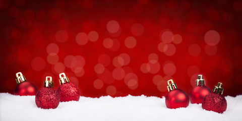 Red Christmas baubles on snow with a red background