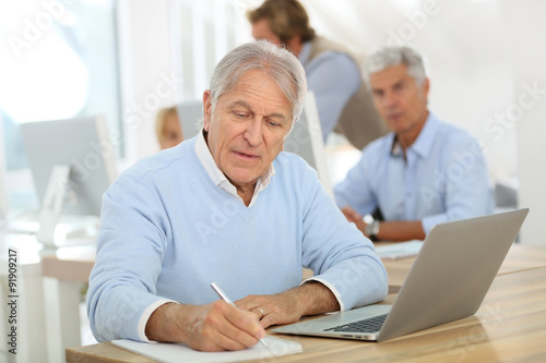 Portrait of senior man working on laptop, training class
