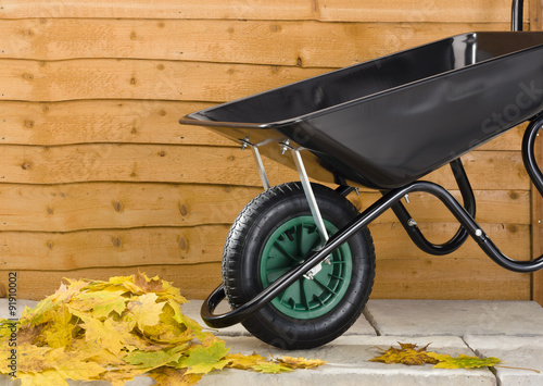 Wheelbarrow and leaves on patio with fence
