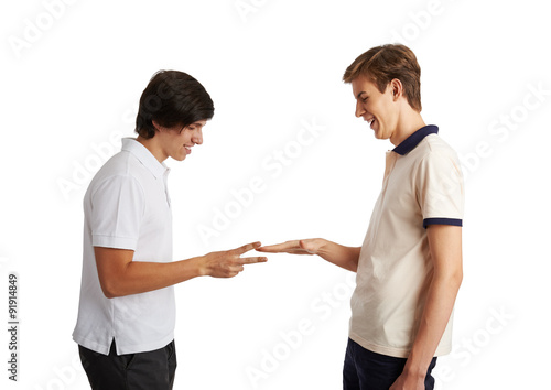 Portrait of two friend playing "stone, scissors, paper" game over white background. Concept of youth, fun and leisure activity. 
