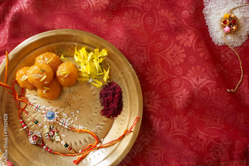 Top View of a plate containing Rakhi and ladoo with sindoor and some flowers marking the religious celebration of Raksha Bhandan. photo