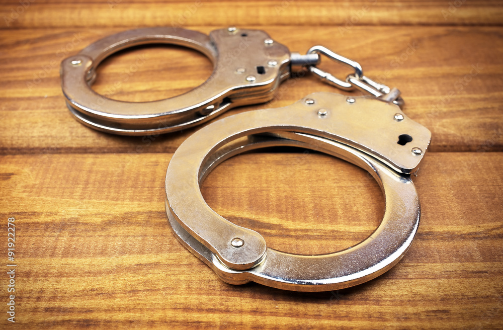 Steel metallic handcuffs on a wooden table