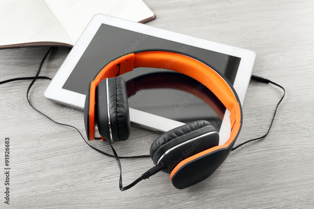 Obraz premium Headphones with tablet and notebook on wooden table close up