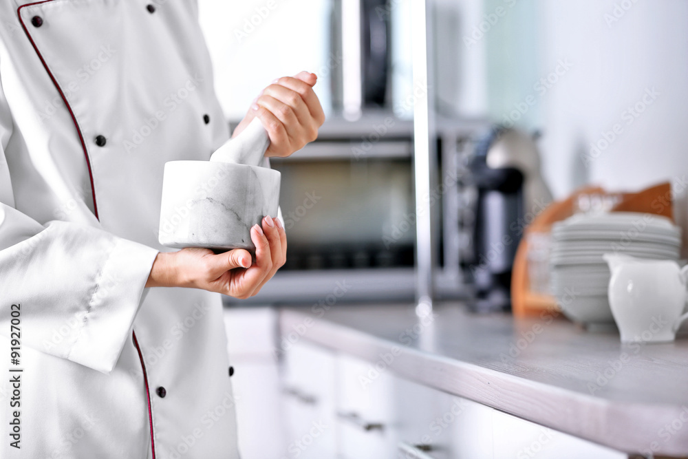 Cook hands with mortar with herbs on bright background Cook hands with mortar with herbs on bright background